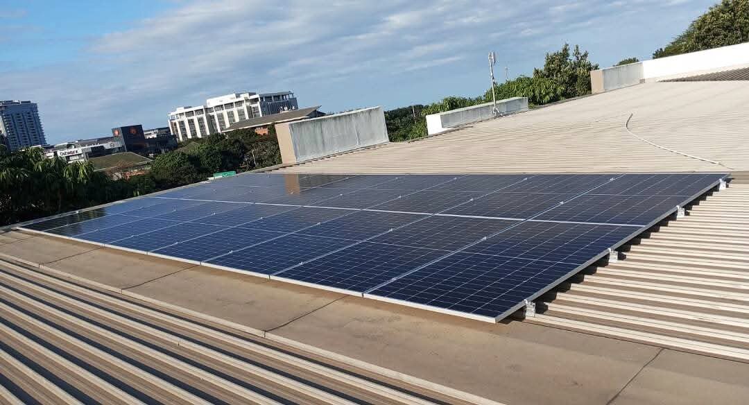 Commercial rooftop solar panel installation with a Durban skyline backdrop