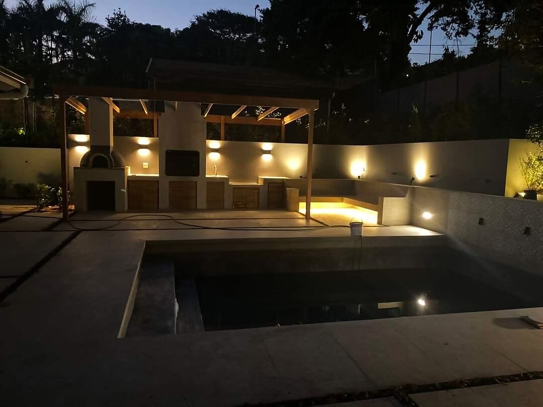 Illuminated outdoor entertainment area with pool and pergola at dusk in Durban