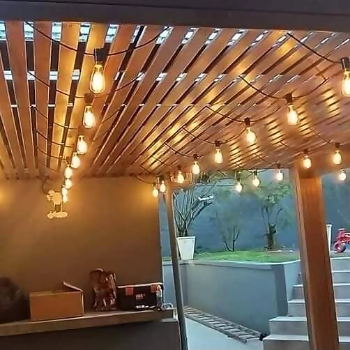 Festoon string lighting installed under a timber pergola at dusk